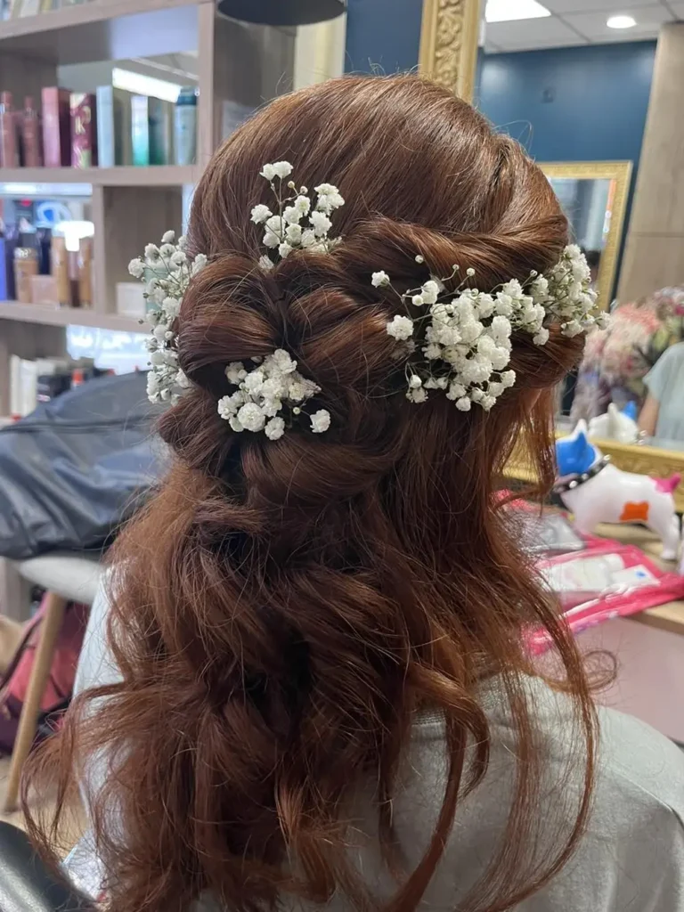 Une coiffure élégante avec des tresses et des fleurs blanches insérées.
